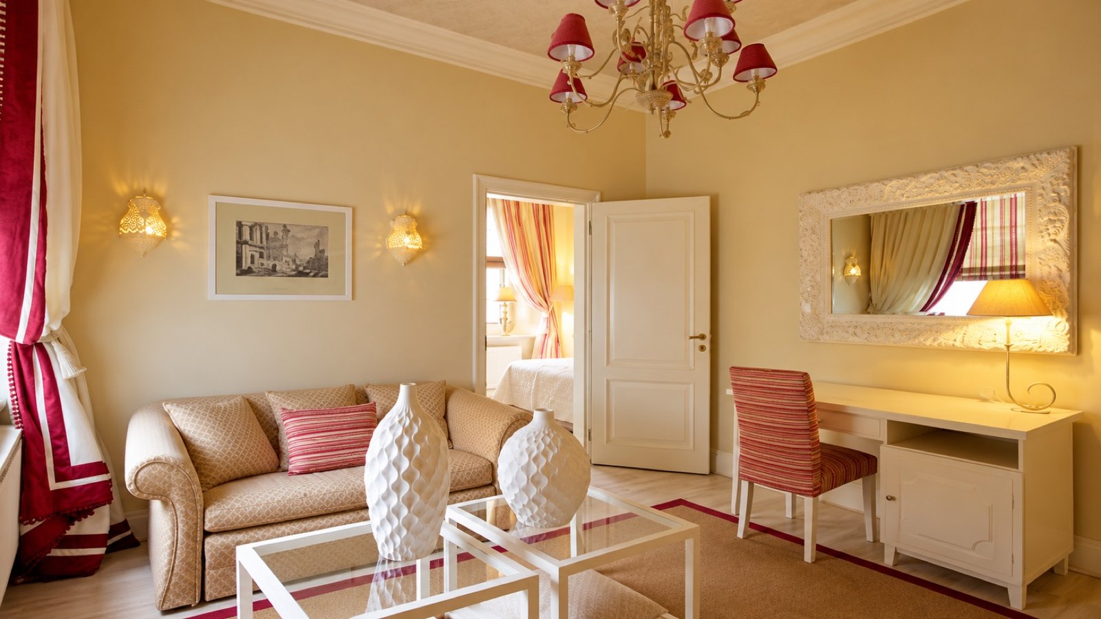 A warm sitting room with a chandelier and writing desk